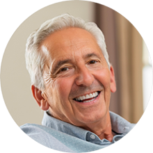 portrait image of older gentleman with blue shirt and white hair smiling